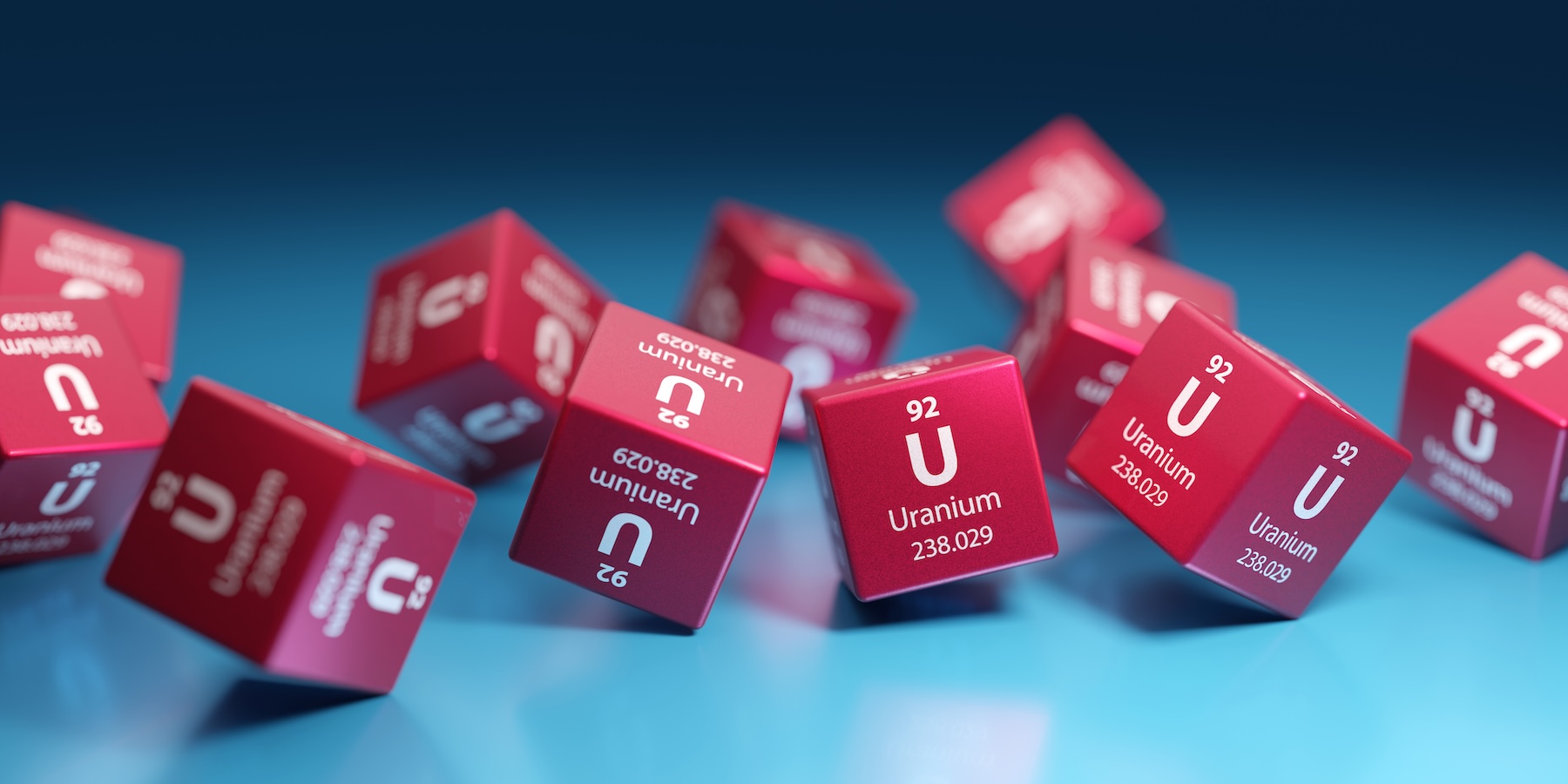 Red cubes printed with 'Uranium' and the atomic data (92, 238.029) scattered on a blue surface, conveying uranium imagery